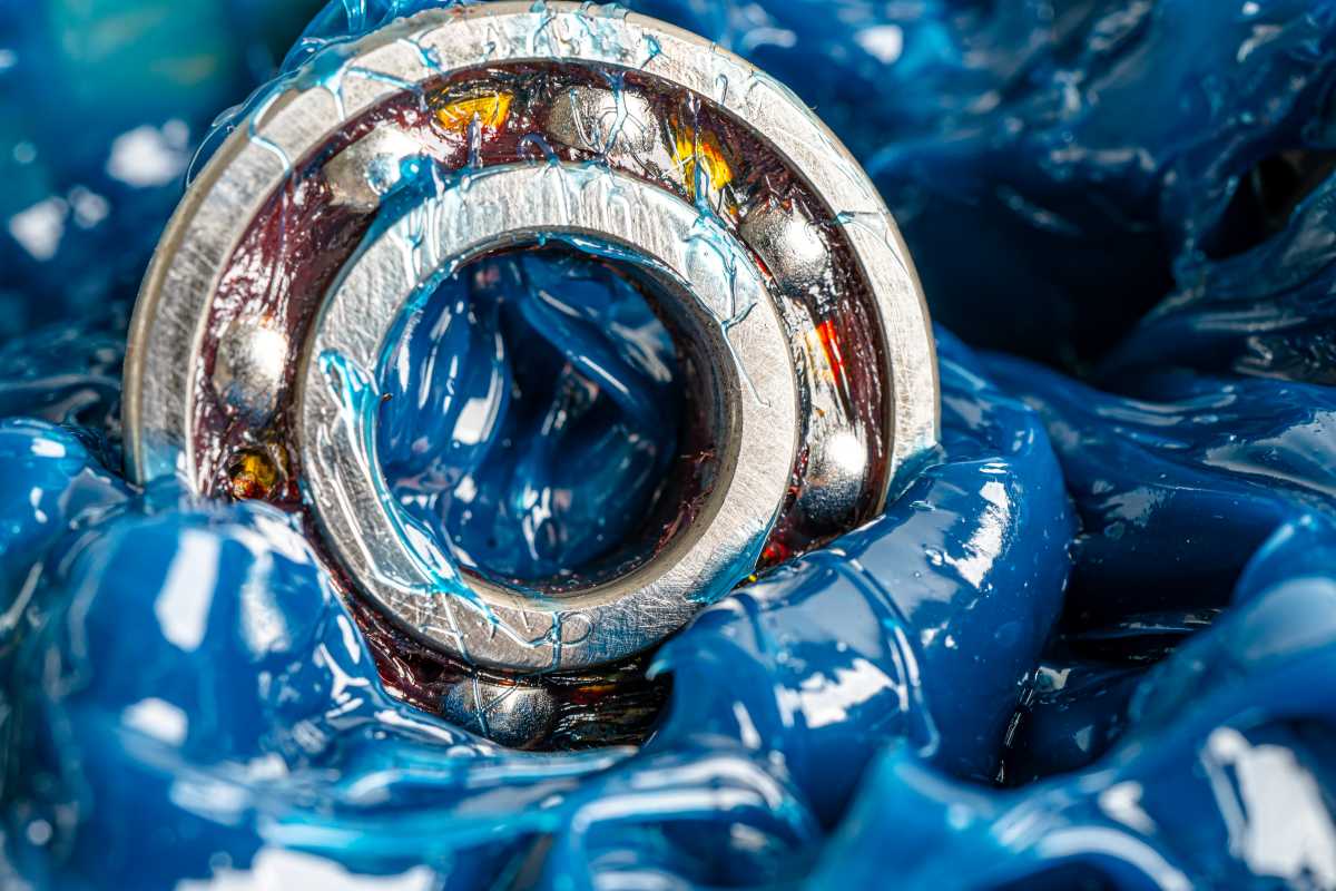 A imagem mostra um rolamento metálico coberto por uma quantidade generosa de graxa azul.