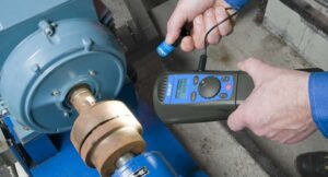 Técnico inspeciona máquina com estroboscópio digital.